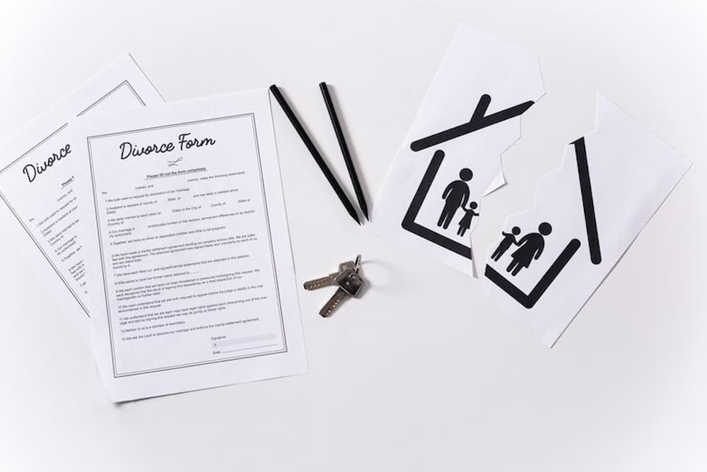 Papeles de divorcio junto a dibujo de casa roto