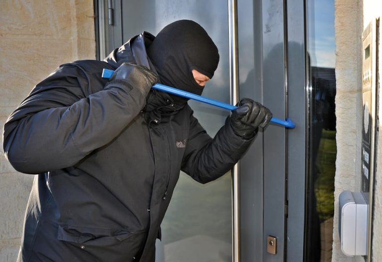 Hombre con máscara forzando cerradura de casa