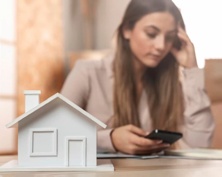 Casa en primer plano con mujer preocupada al fondo