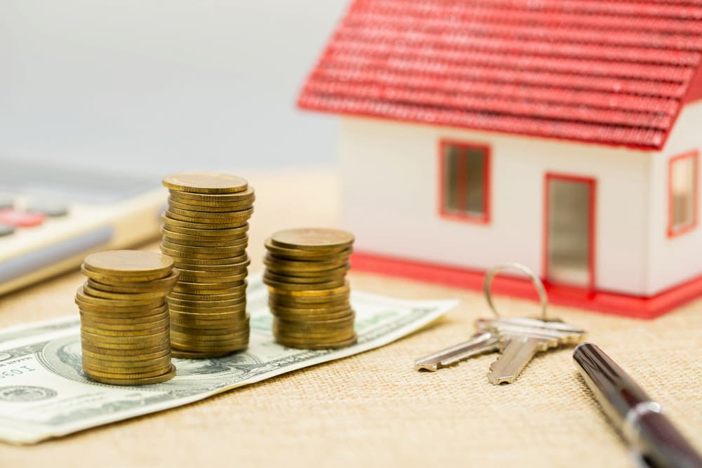 Figura de casa junto a llaves y dinero