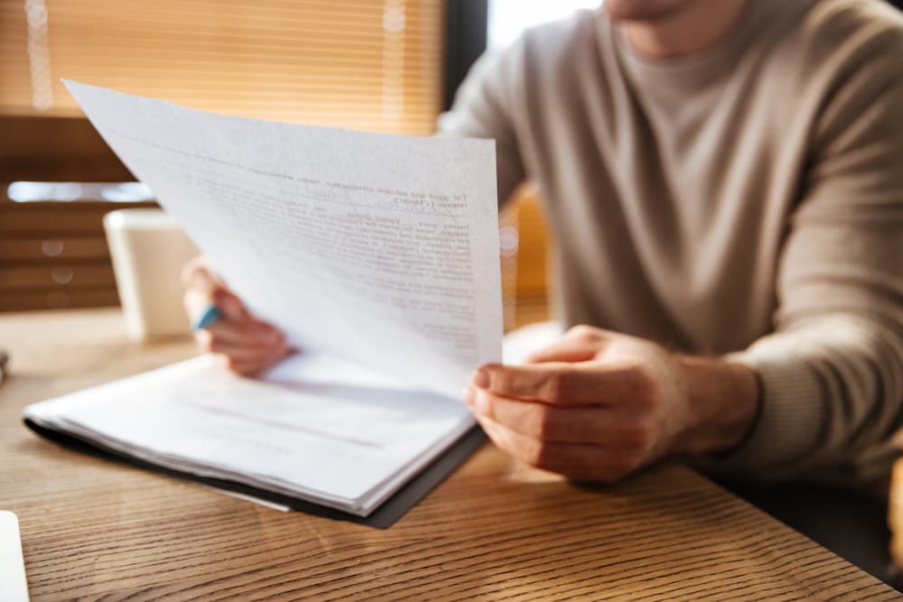 Hombre leyendo papeles de hipoteca antes de firmar