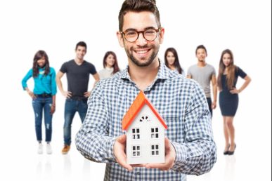 Hombre sosteniendo figura de casa con personas detrás